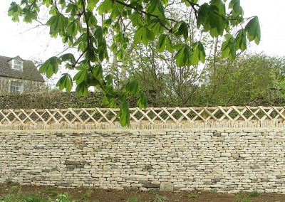 Rustic Sweet Chestnut picket trellis surmounted on top of a Cotswold dry stone wall